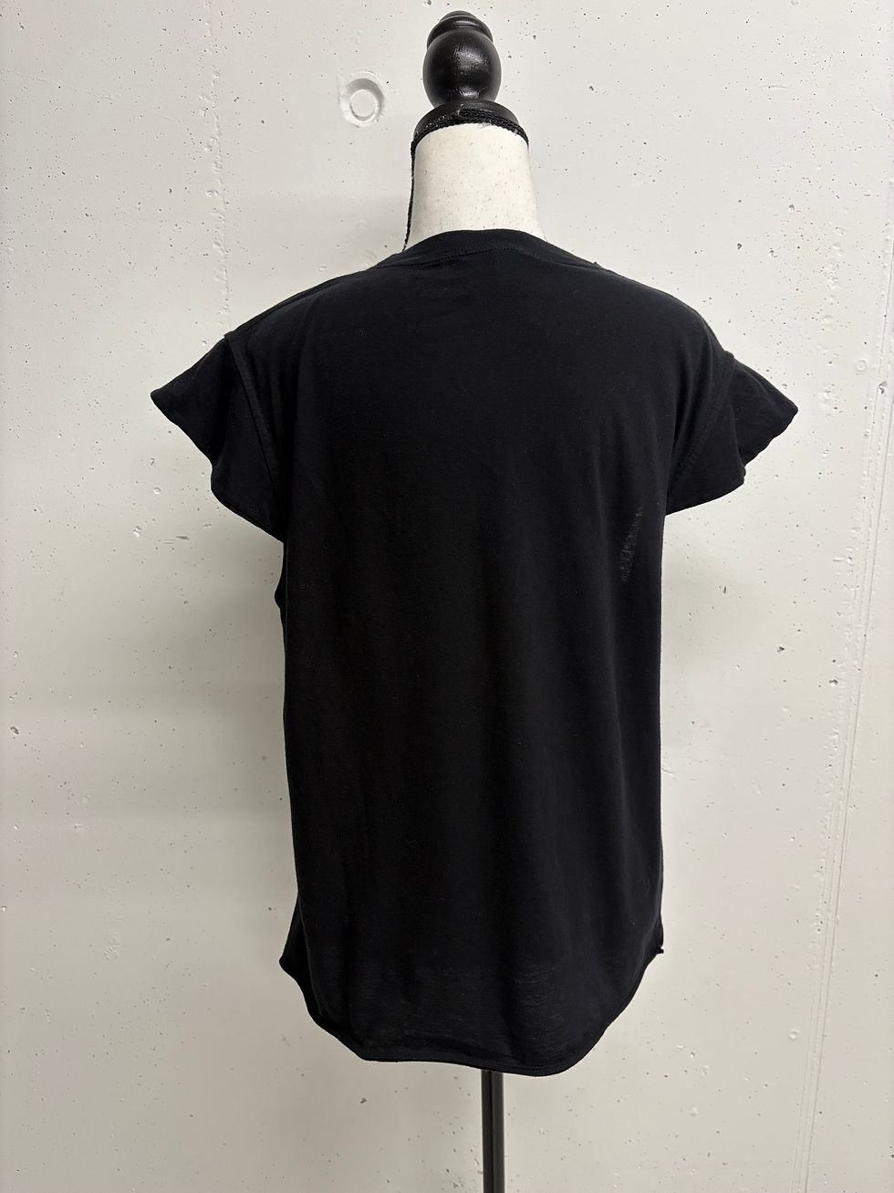 Miniaturbild: Schwarzes T-Shirt auf Schaufensterpuppe, Rückansicht. Ein schlichtes, schwarzes Oberteil.