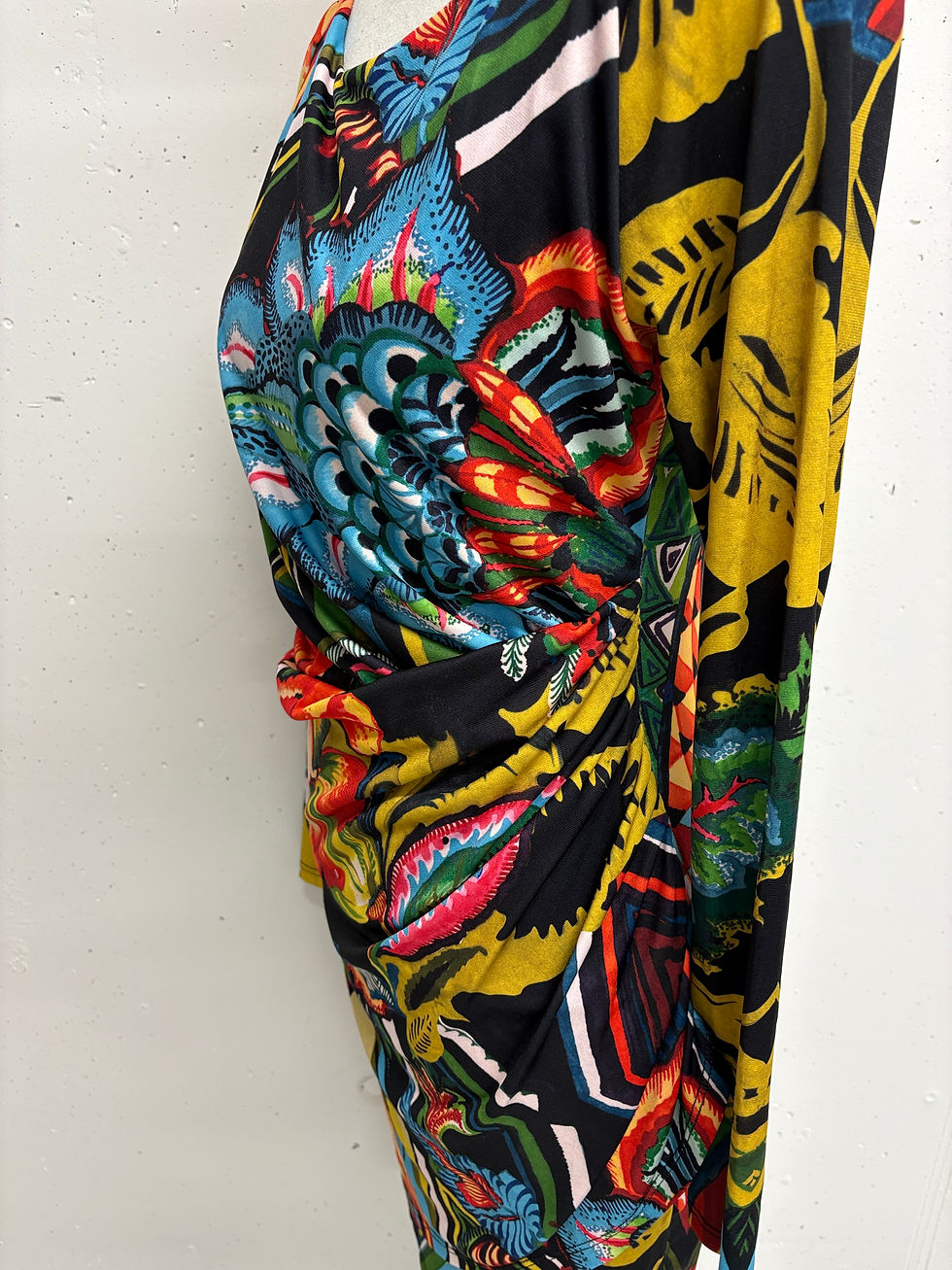 Miniaturbild: Gemustertes Kleid mit farbenfrohen Details. Nahaufnahme zeigt Stofffalten am Körper.
