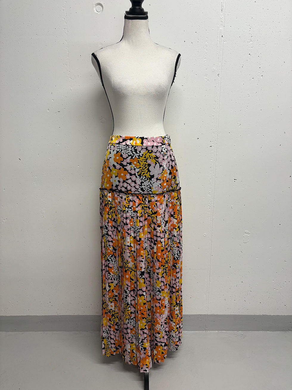 Gemustertes Maxikleid auf Schneiderpuppe für Damen. Blütenmuster und schwarzer Saum.