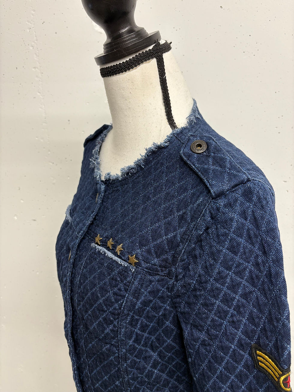 Miniaturbild: Dunkelblaue Jeansjacke mit Sternen auf einem Schaufensterpuppenhals. Stilvolle Modepräsentation.