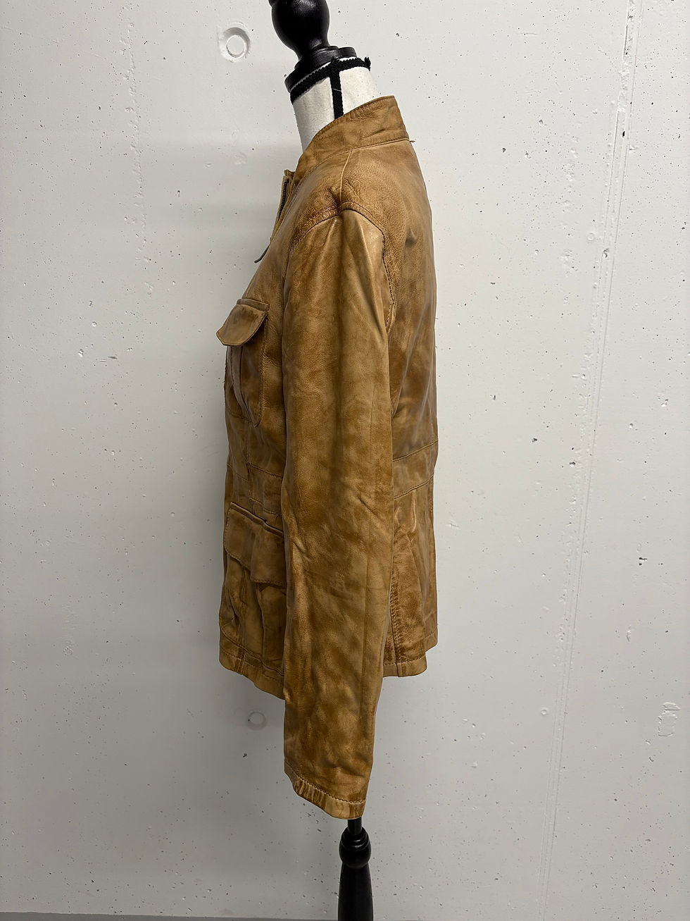 Braune Lederjacke im Profil, mit Taschen, Details und Struktur an einem Model.