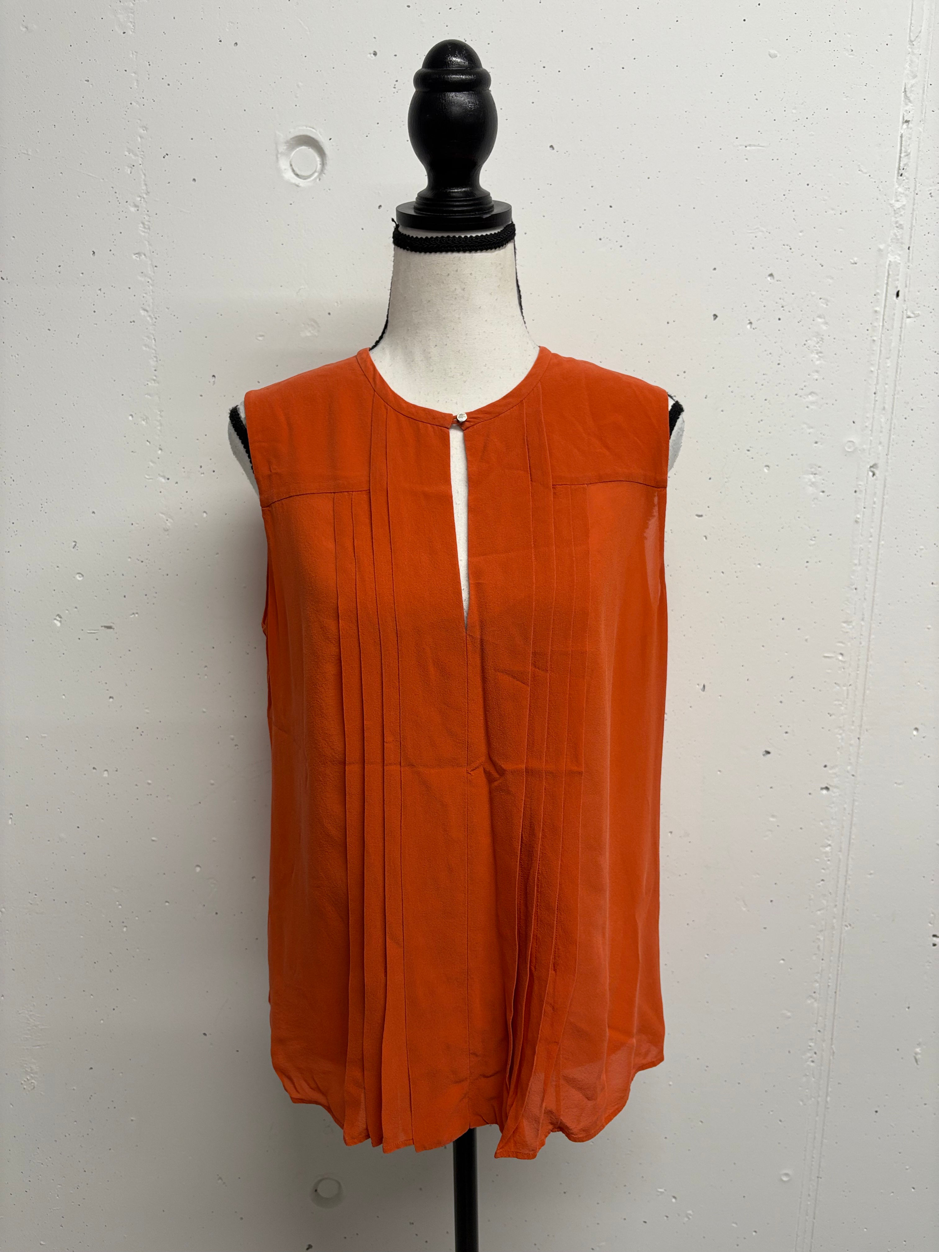 Orangefarbenes Oberteil auf Mannequin ausgestellt. Einfacher Hintergrund.