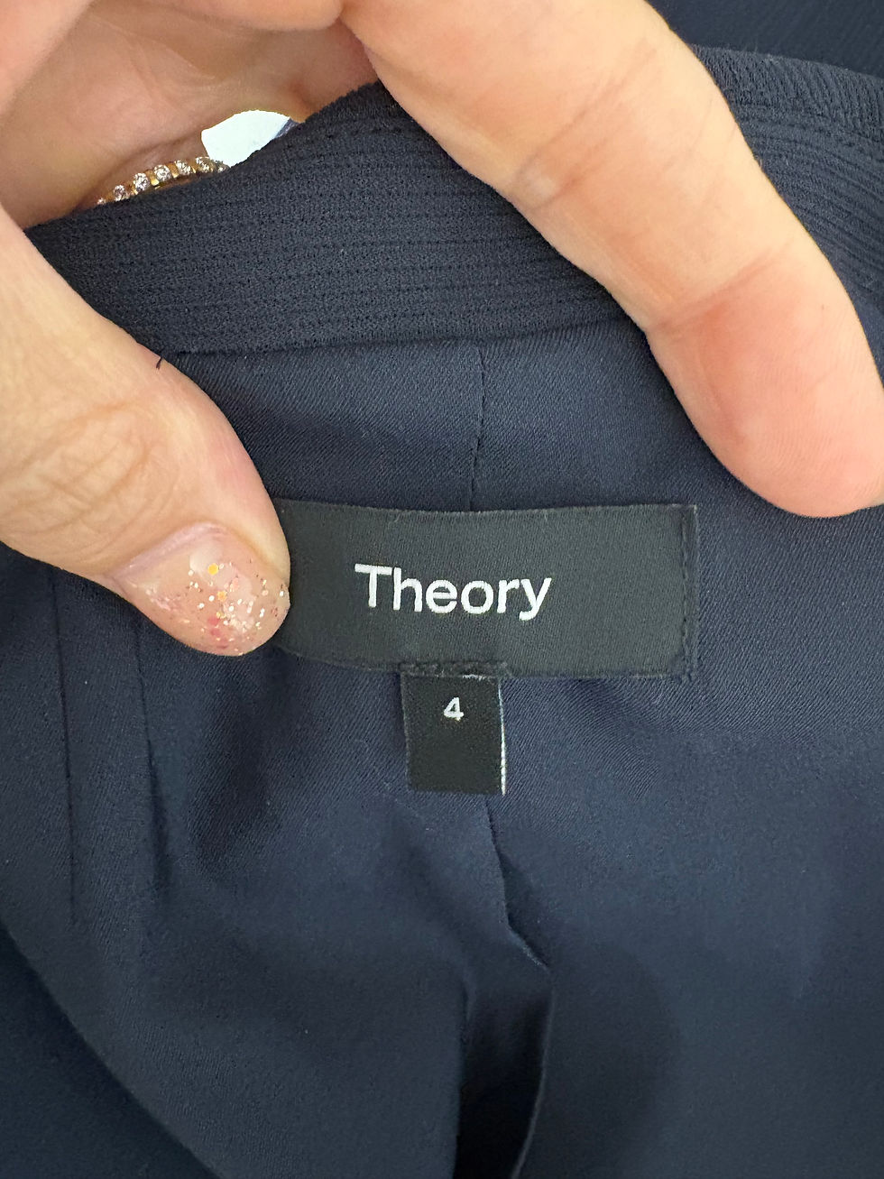 Miniaturbild: Theory label with size 4 on a dark jacket, close-up details.