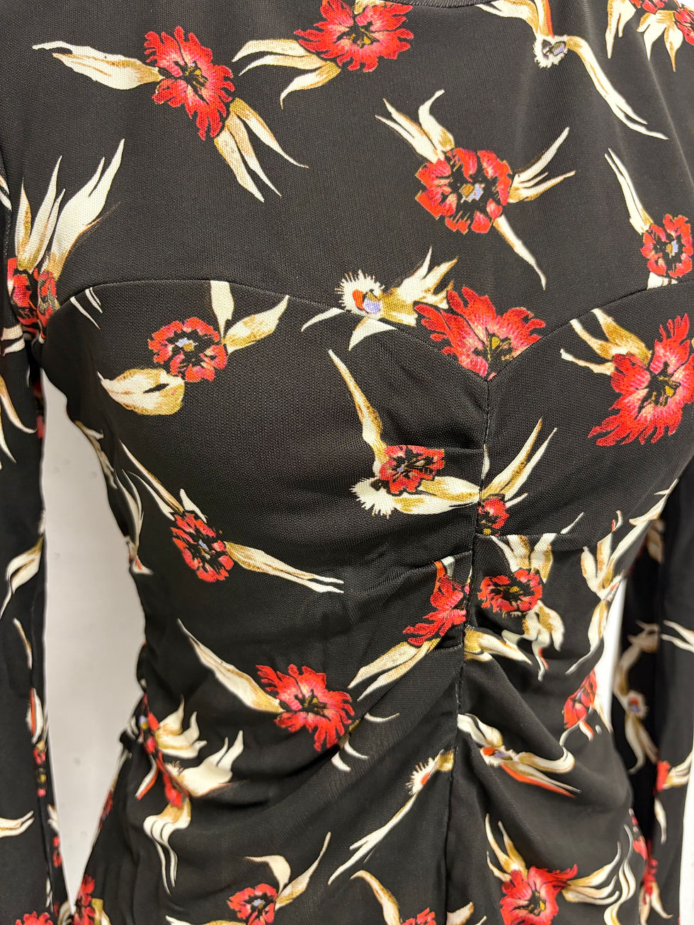 Miniaturbild: Schwarzes Kleid mit Blumenmuster und Raffungen am Ausschnitt, Nahaufnahme.