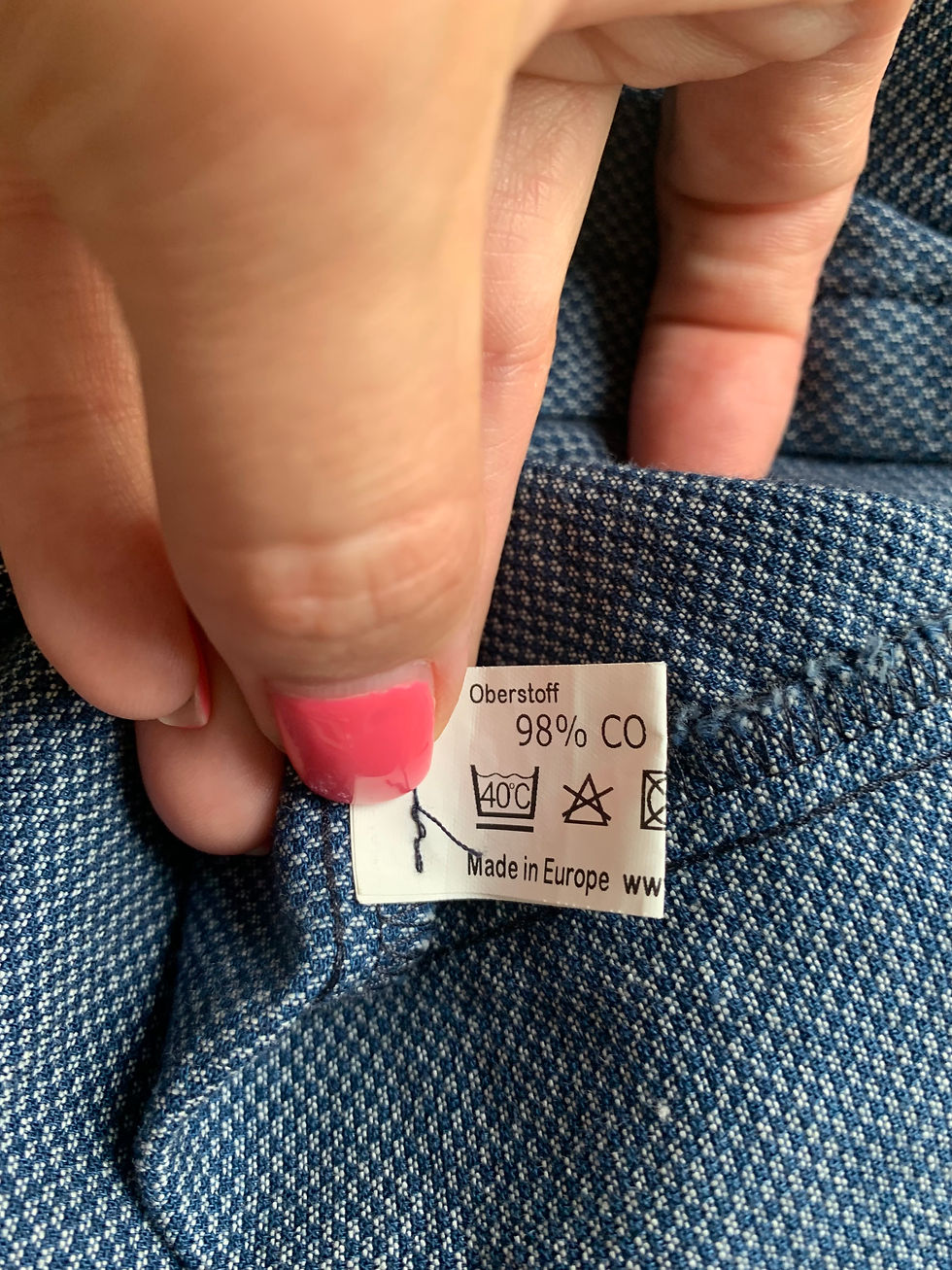 Miniaturbild: Hand hält Textil-Etikett mit Aufdruck: Oberstoff, 98% CO, Made in Europe