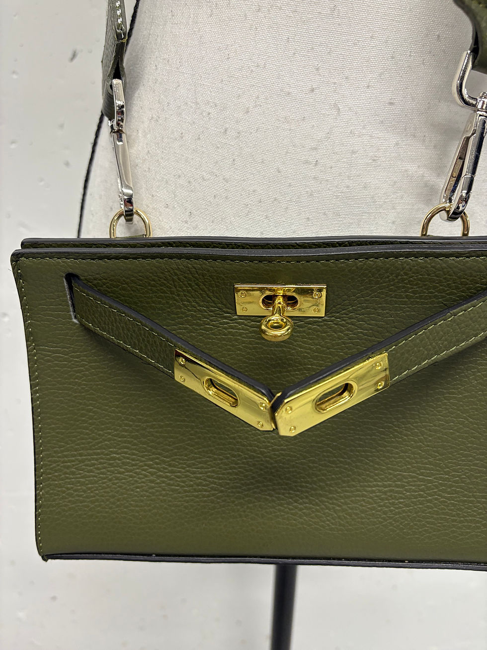 Miniaturbild: Grüne Lederhandtasche mit goldfarbenen Verschlüssen und Kettenriemen nah aufgenommen.