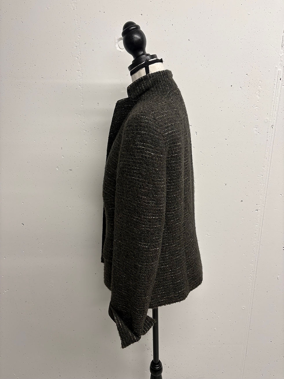 Dunkelbraune Jacke, seitliche Ansicht, auf einem Kleiderständer vor weißer Wand.