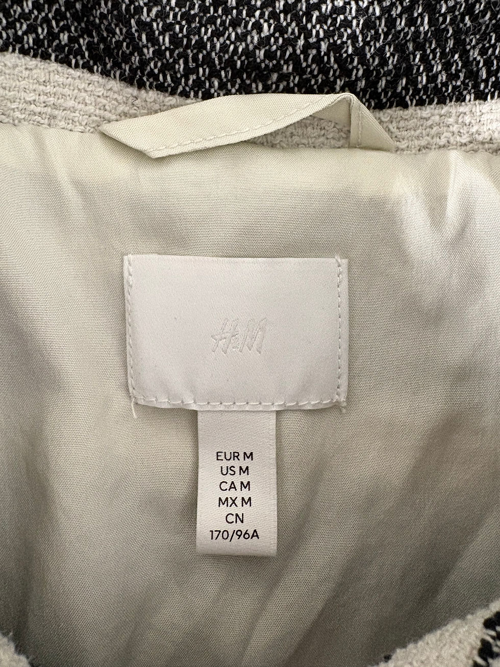 Miniaturbild: H&M Etikett EUR M US M CAM M MX M CN 170/96A weißes Kleidungsstück Detail Nahaufnahme