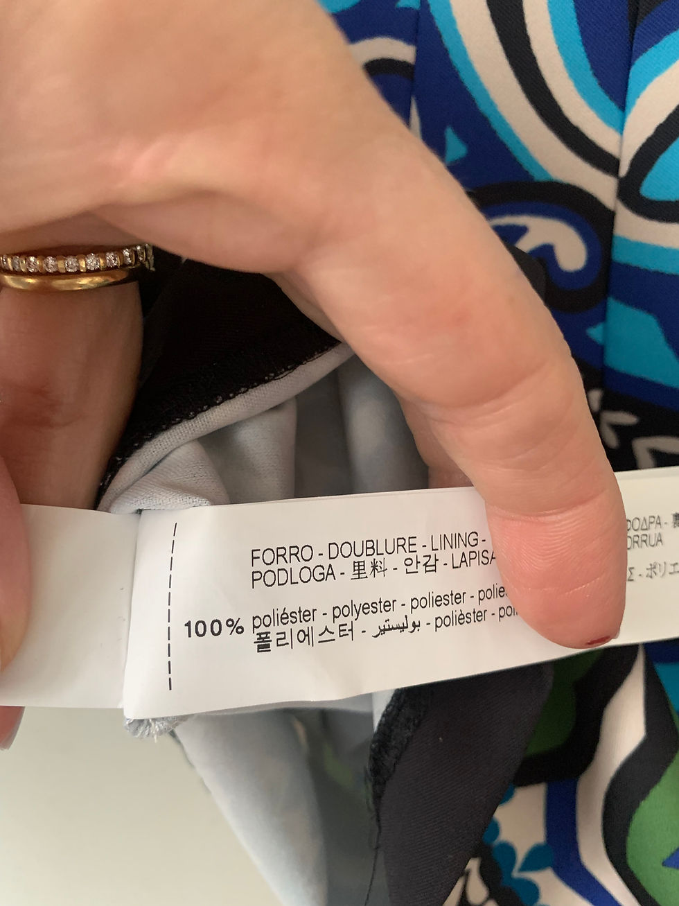 Miniaturbild: Hand holding clothes tag: Forro, 100% Polyester with multi-language text.