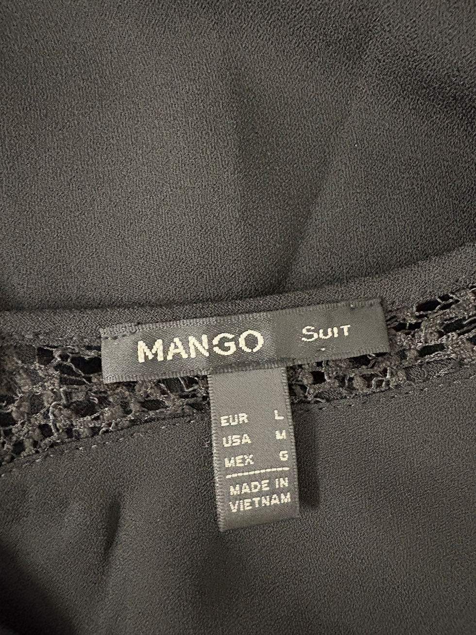 Miniaturbild: Schwarzes Mango-Suit-Kleidungsstück mit Etikett und Grössenangaben, hergestellt in Vietnam.