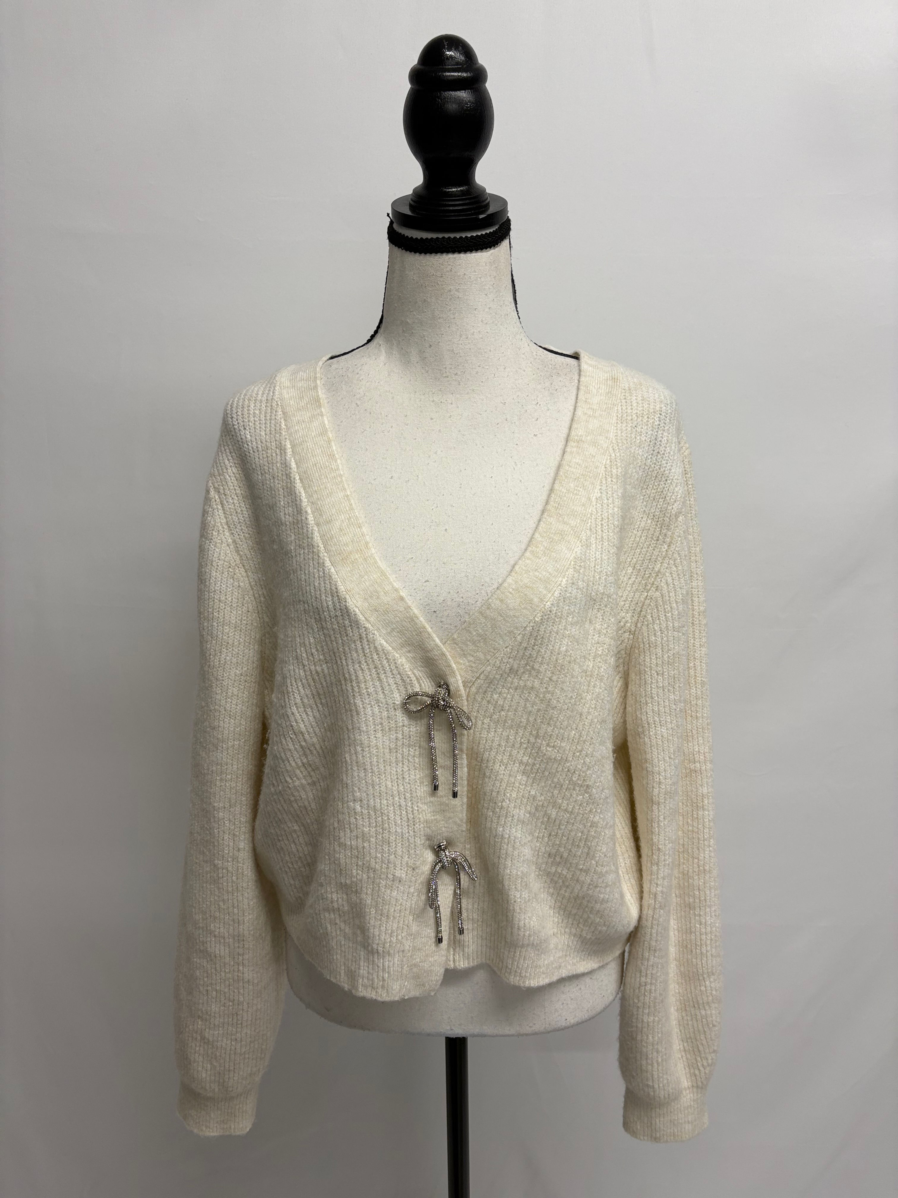 Cremefarbene Strickjacke mit glitzernden Verschlüssen auf einer Schaufensterpuppe. PERFECT CASHMERE Kaschmirschal (NP 169.-)