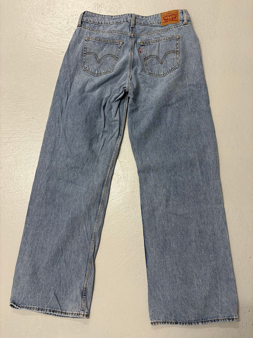 Miniaturbild: Hellblaue Jeans, Levi's, Details am Po, auf hellem Untergrund, von hinten gesehen.