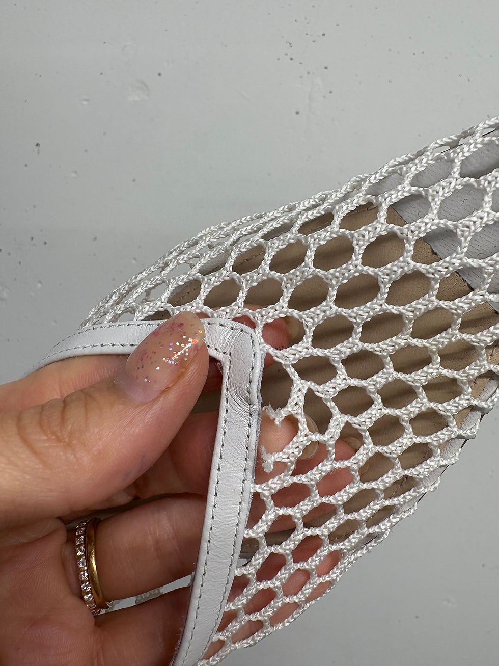 Miniaturbild: Nahaufnahme einer Hand mit weißem Netzschuh; Detailansicht des Schuhs