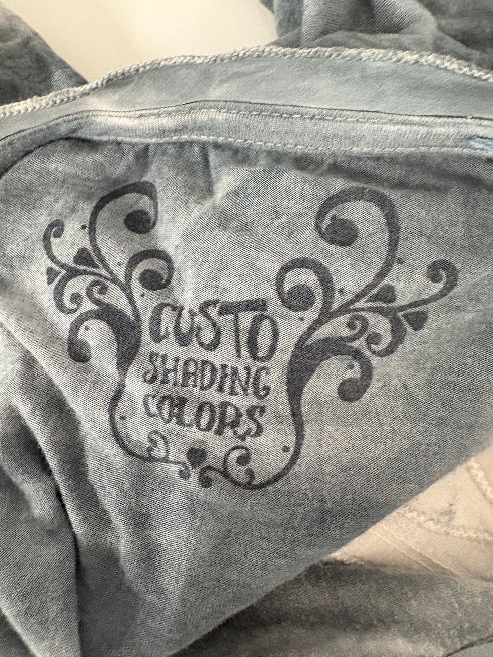 Miniaturbild: Nahaufnahme eines grauen Stoffes mit „CUSTO SHADING COLORS“ Schriftzug.