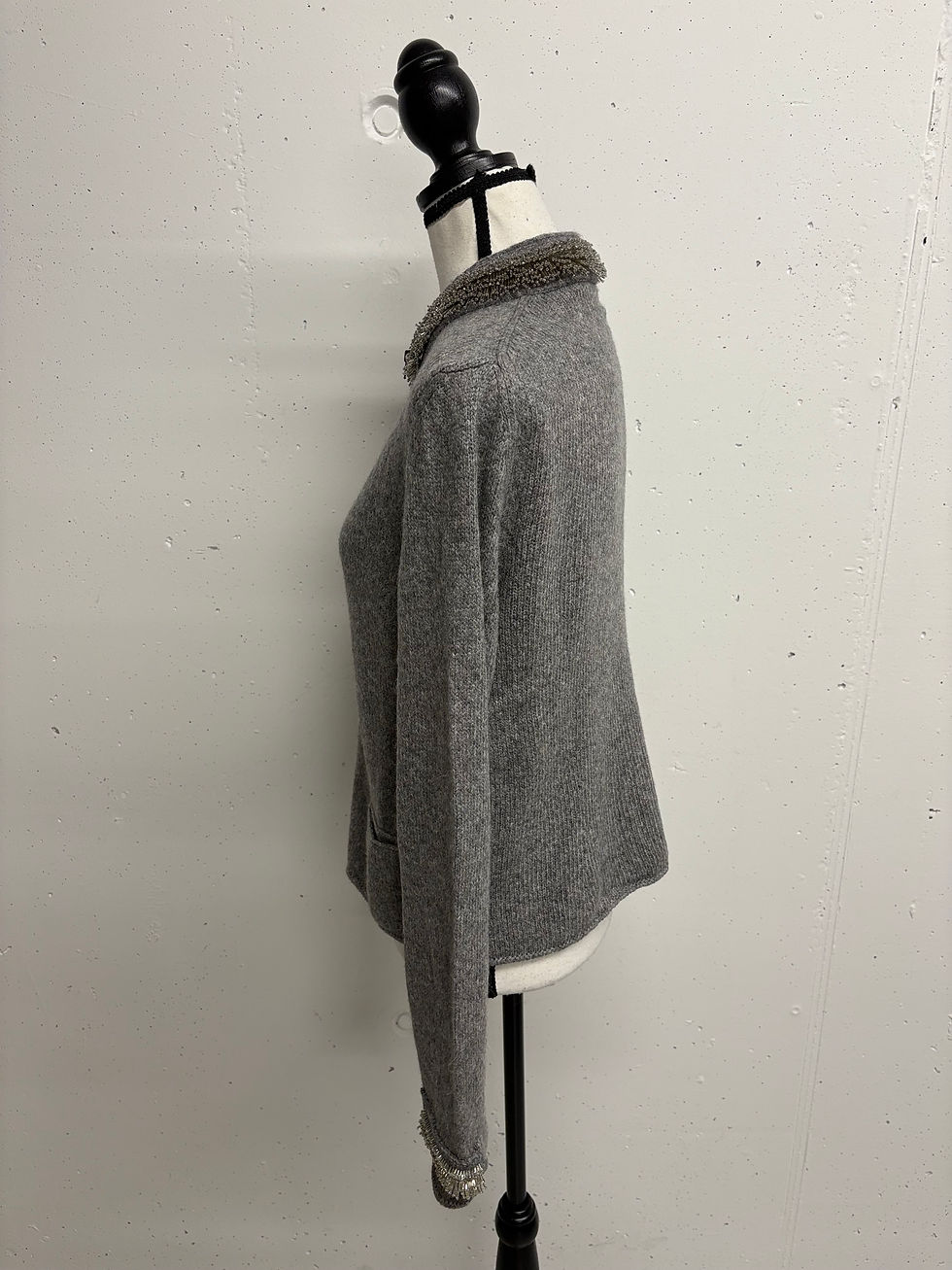 Grauer Pullover mit Fellkragen auf Schaufensterpuppe vor weißem Hintergrund.