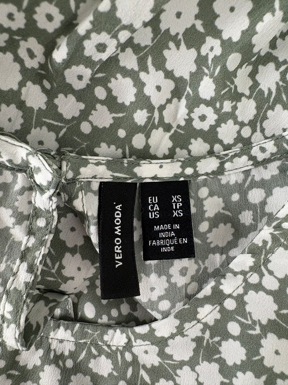 Miniaturbild: Nahaufnahme eines floralen VERO MODA Hemdes mit Etikett XS. Made in India.