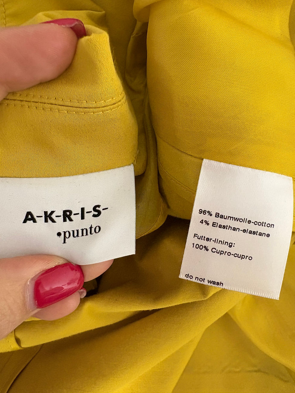 Miniaturbild: AKRIS *punto labels, 96% Baumwolle-cotton, 4% Elasthan-elastane, details on yellow fabric background.