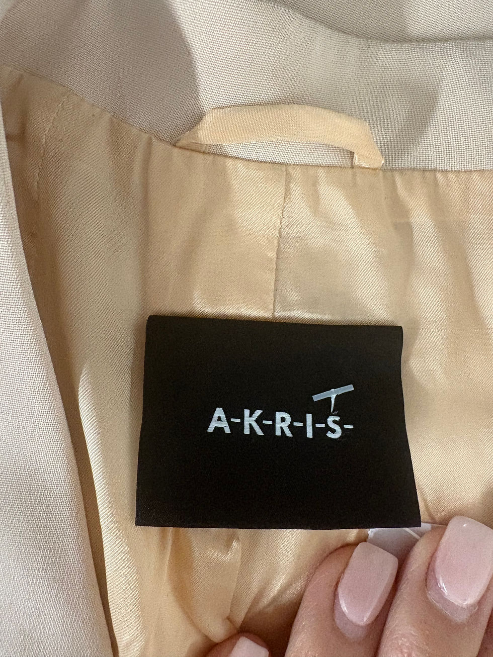 Miniaturbild: Nahaufnahme eines schwarzen Etiketts mit der Aufschrift AKRIS für Kleidung.