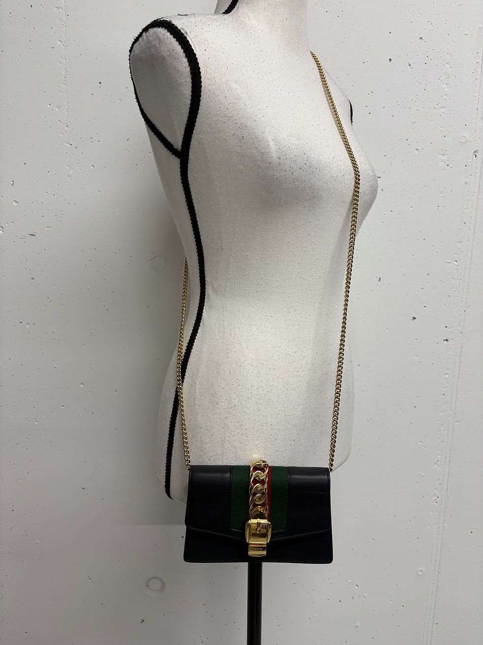 Miniaturbild: Schwarze Gucci-Tasche mit goldener Kette auf einem Schaufensterpuppen-Körper.