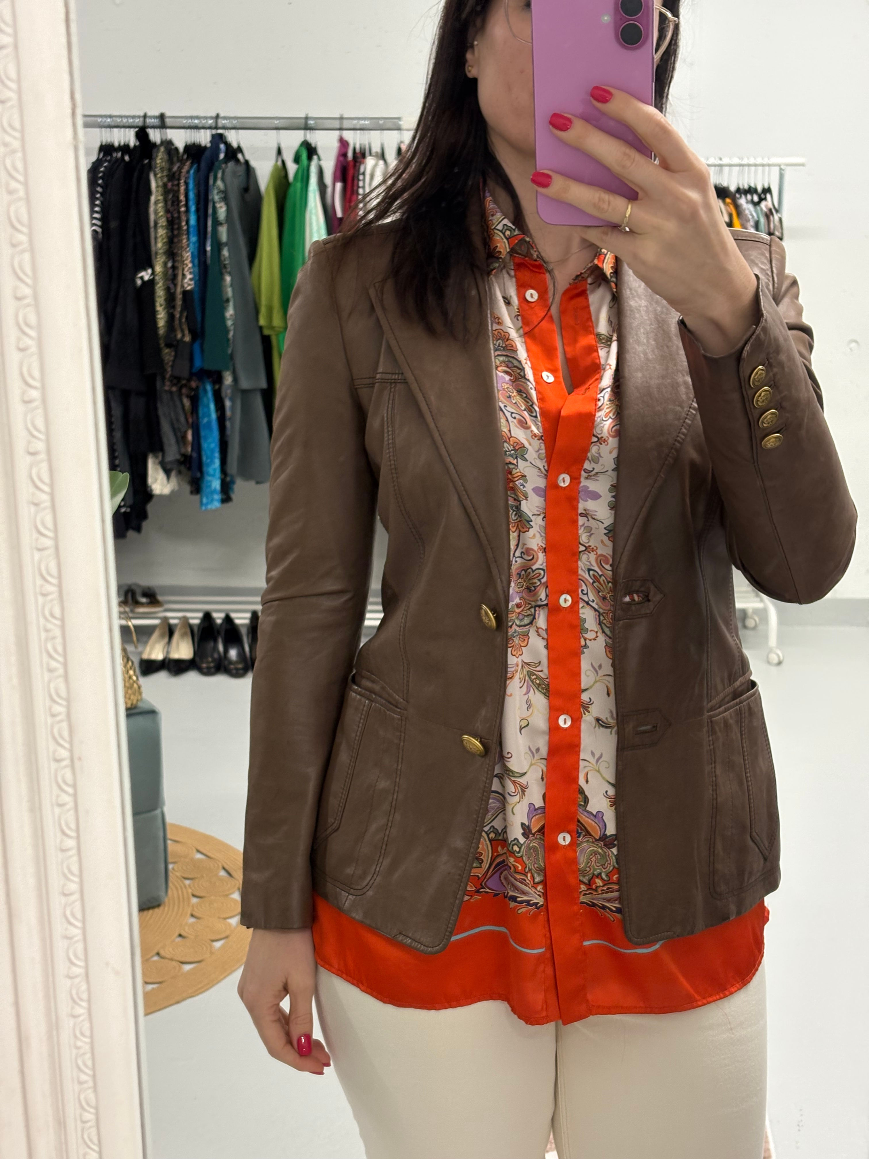 Frau trägt braune Lederjacke, orangefarbenes Hemd; RALPH LAUREN Jacke; Kleidung Hintergrund.