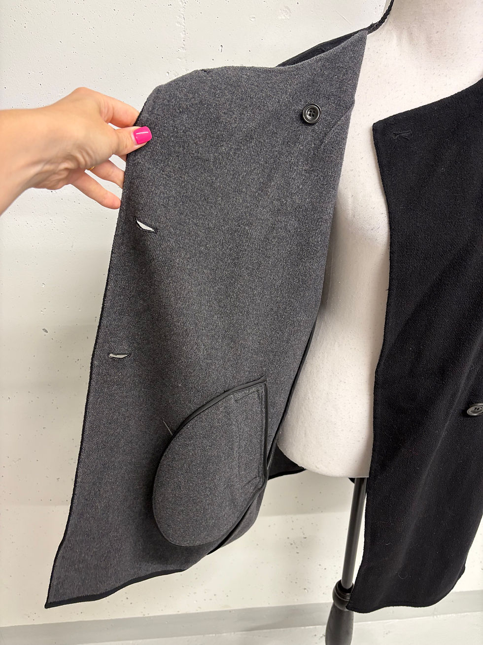 Miniaturbild: Dunkelgraue Jacke mit Knöpfen und offener Tasche, Nahaufnahme, Detailaufnahme.