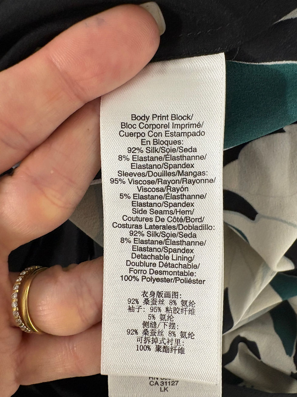 Miniaturbild: White clothing tag with text about materials and percentages on black fabric