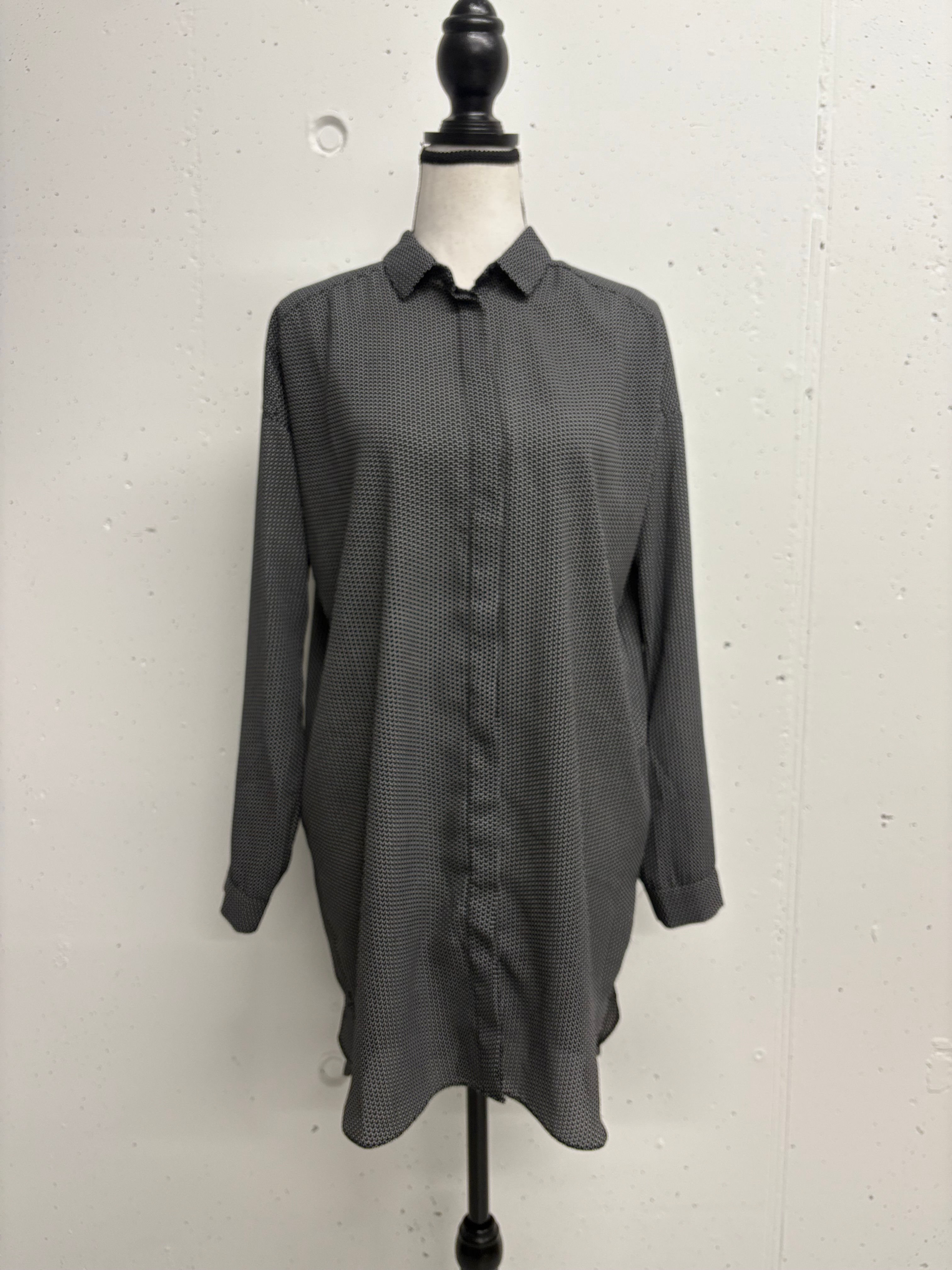 Graues Hemd auf Büste, lange Ärmel, Knopfleiste, vor weißem Hintergrund.