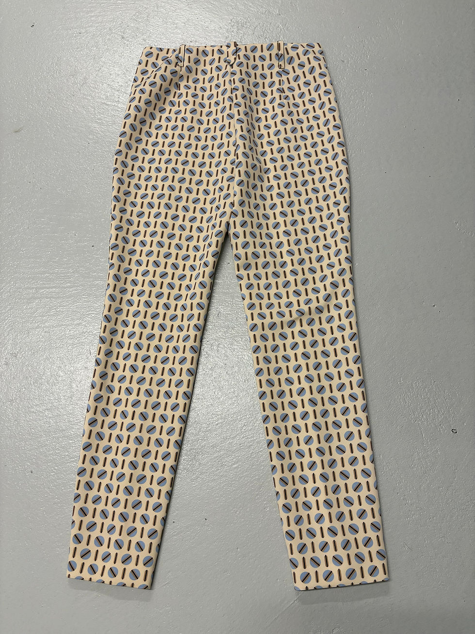 Miniaturbild: Hose mit Muster liegend, beige, blau und gelb, auf grauem Untergrund.