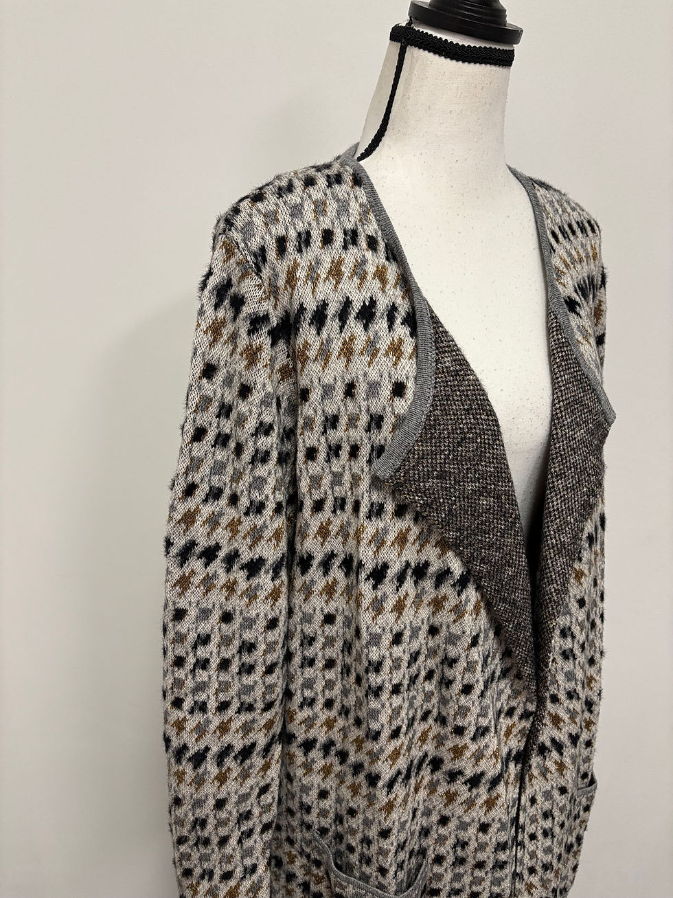 Gemusterte Strickjacke auf einer Schaufensterpuppe mit grauem Kragen und Musterung.