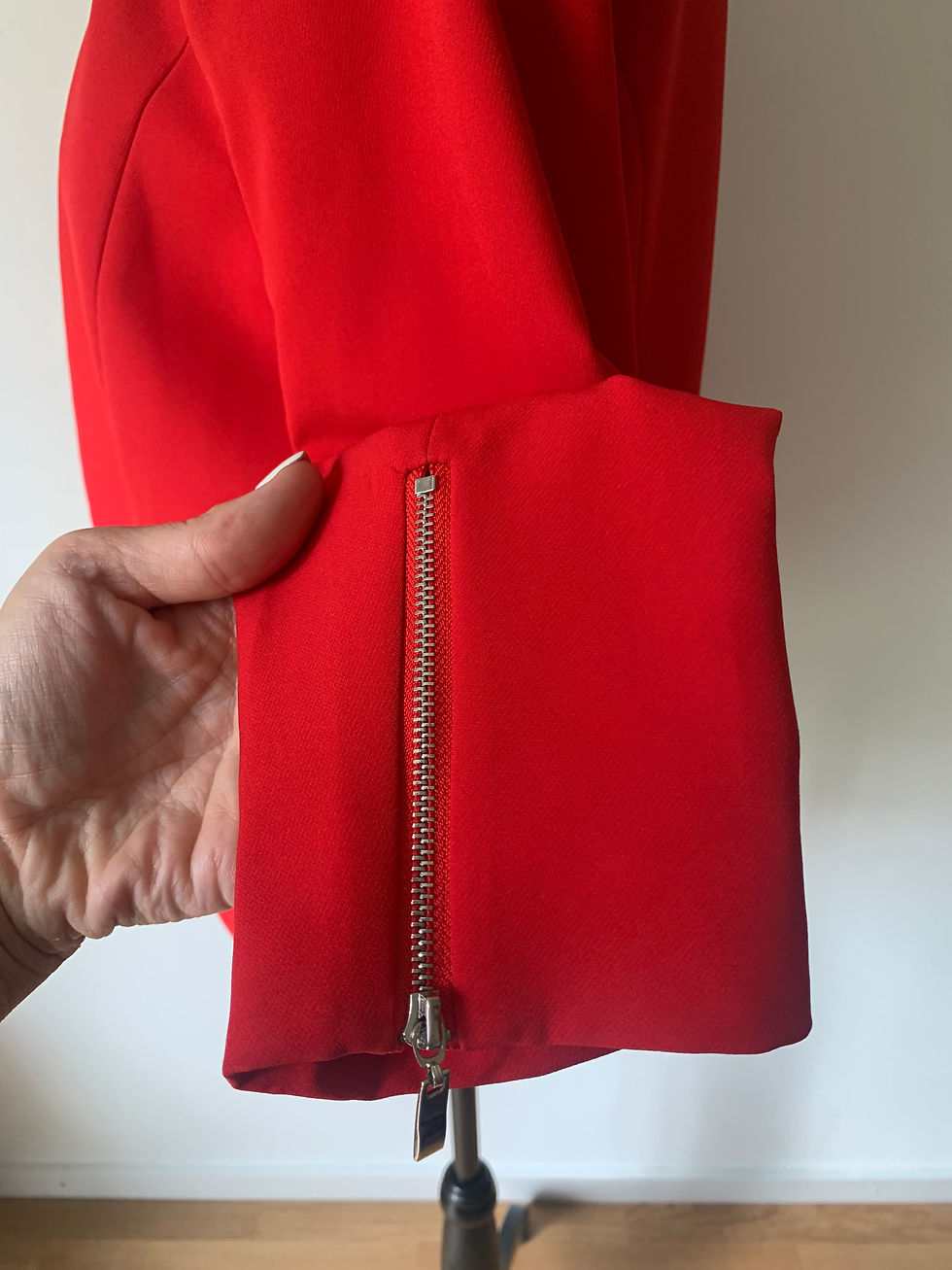Miniaturbild: Rote Hose, Detailansicht: Hand hält Reißverschluss am Hosenbein und roter Stoff