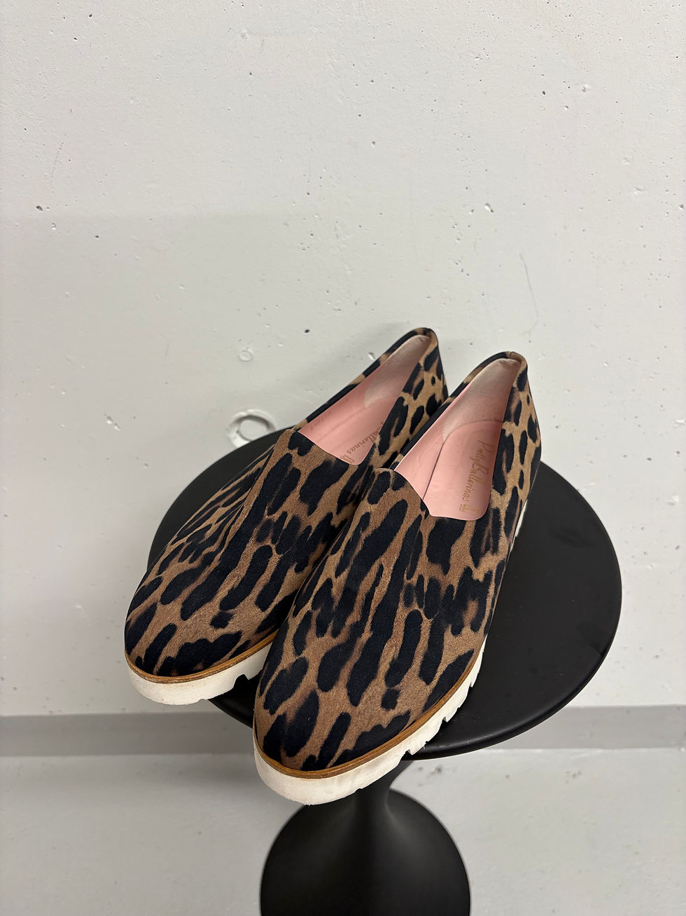 Miniaturbild: Paar Leopardenmuster Schuhe auf einem schwarzen runden Tisch, Mode.