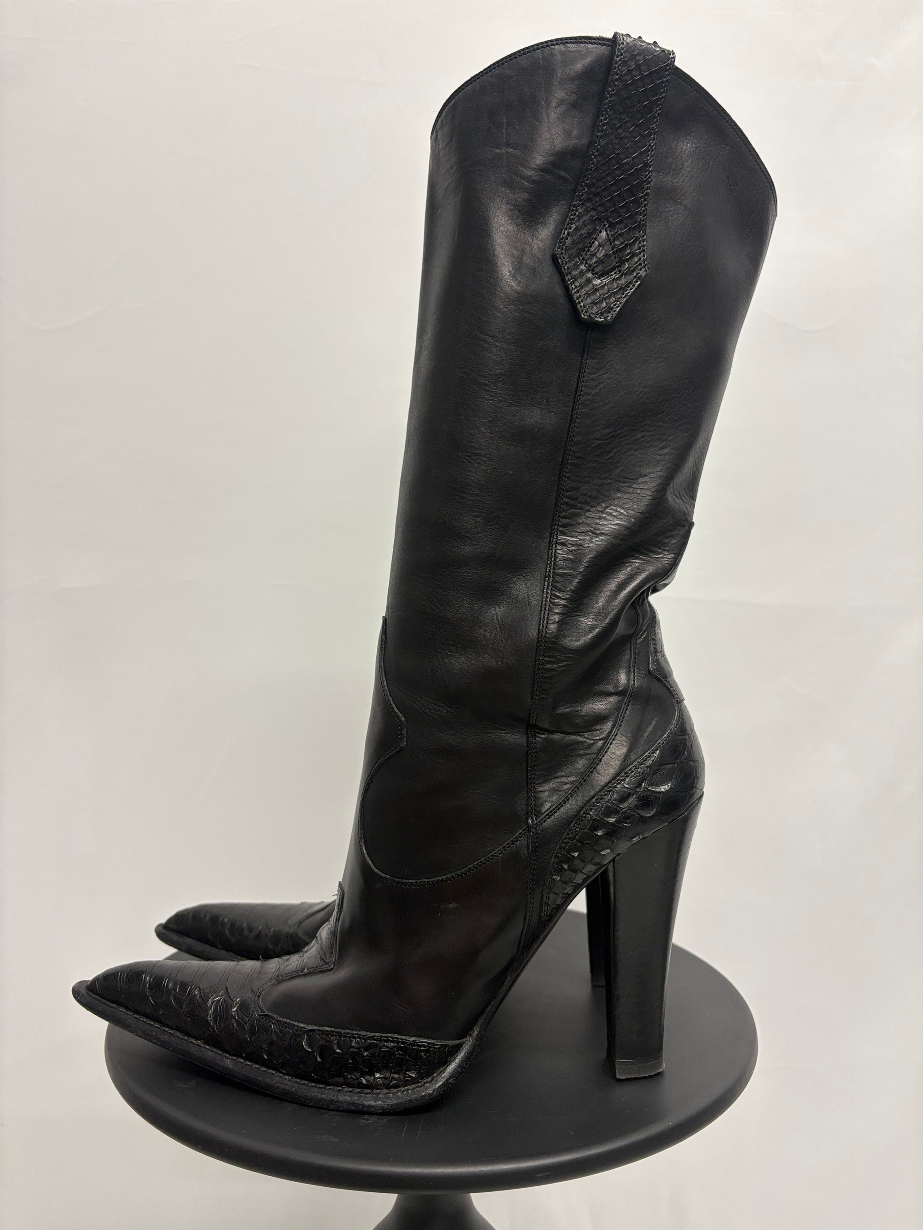 Schwarzer Lederstiefel, Seitenansicht, hoher Absatz, spitz zulaufende Zehen, elegantes Design.