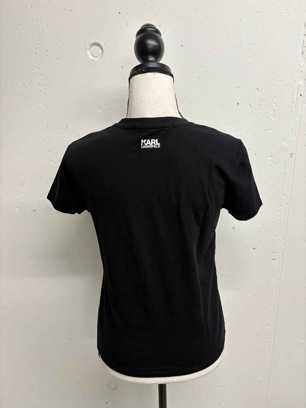 Miniaturbild: Schwarzes Karl Lagerfeld T-Shirt Rückansicht mit weißem Logo auf hellem Hintergrund.