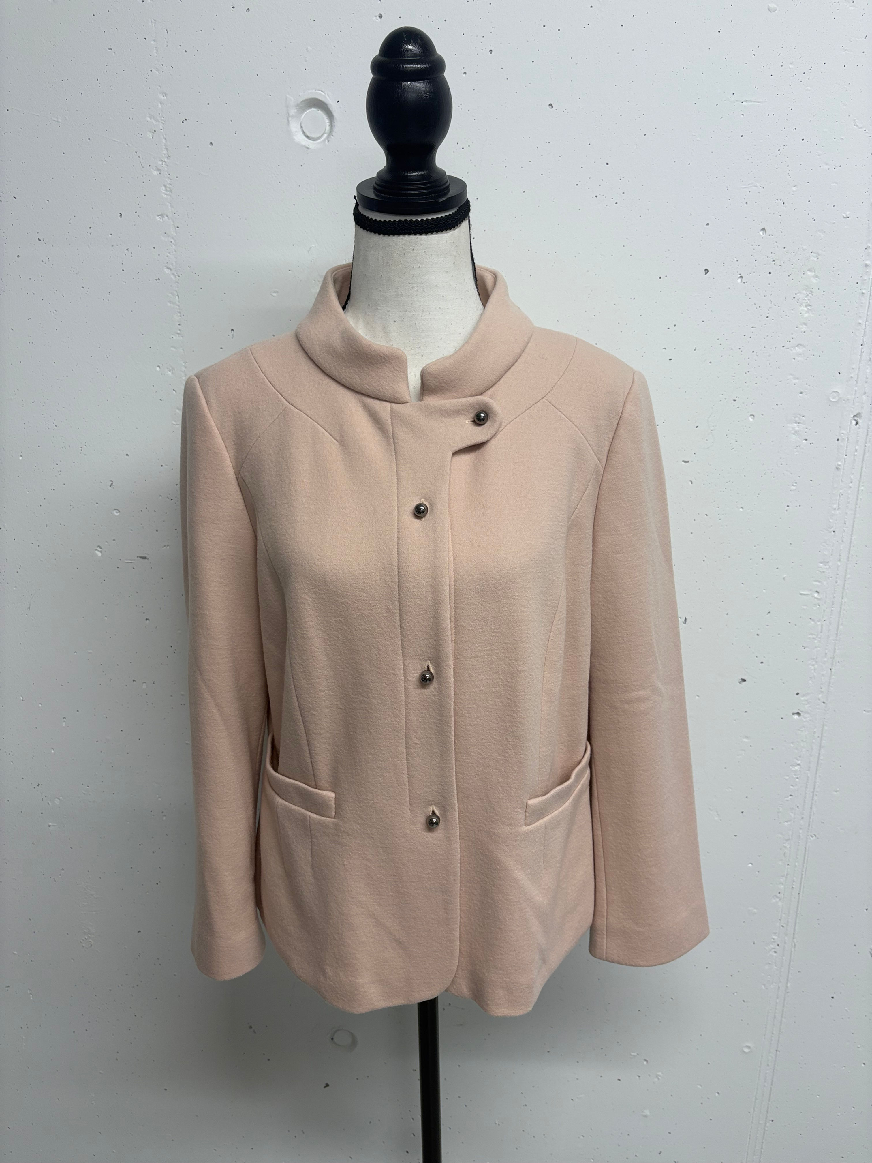 Hellrosa Jacke mit Knöpfen auf einer Schaufensterpuppe vor hellem Hintergrund.