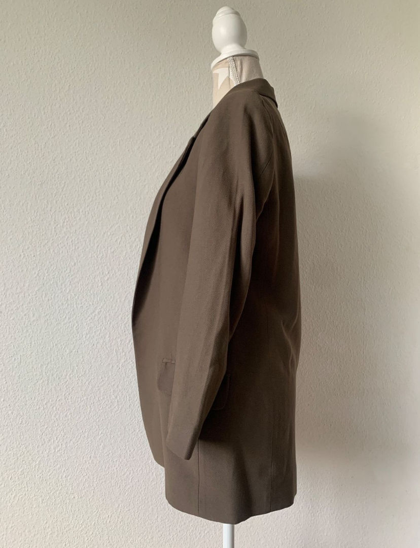 Miniaturbild: Brauner Blazer auf einem Büstenständer vor einer weißen Wand