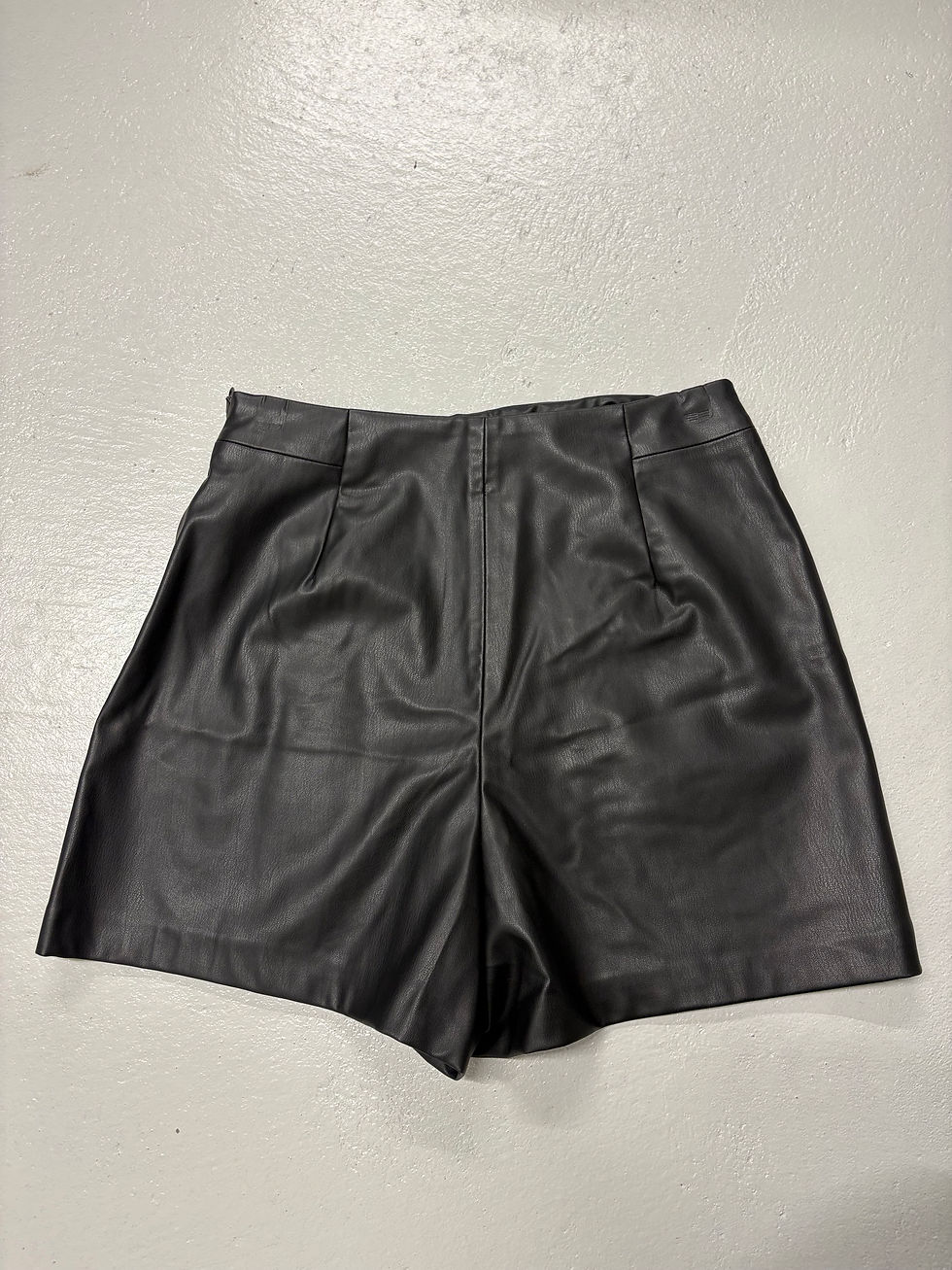 Schwarze Leder-Shorts auf weißem Hintergrund, Modekleidung für Damen, nahansicht.