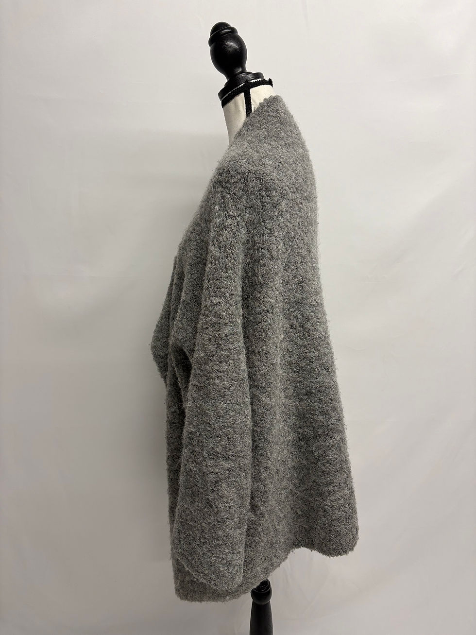 Grauer grob gestrickter Wollpullover auf einer Schneiderpuppe vor weißem Hintergrund.