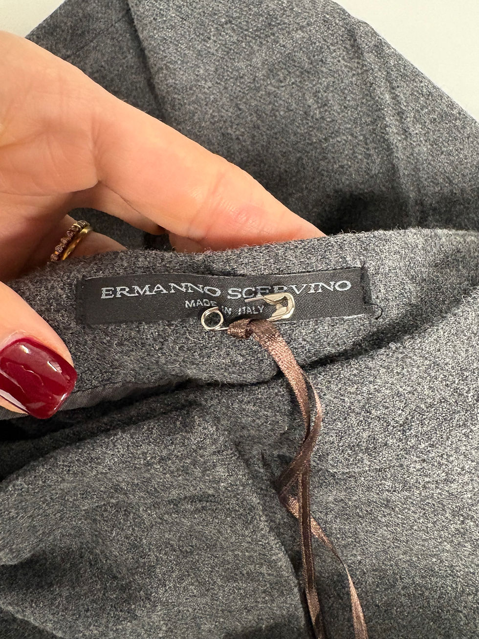 Miniaturbild: Hand hält das Label von Ermanno Scervino, Made in Italy, grauer Hintergrund.
