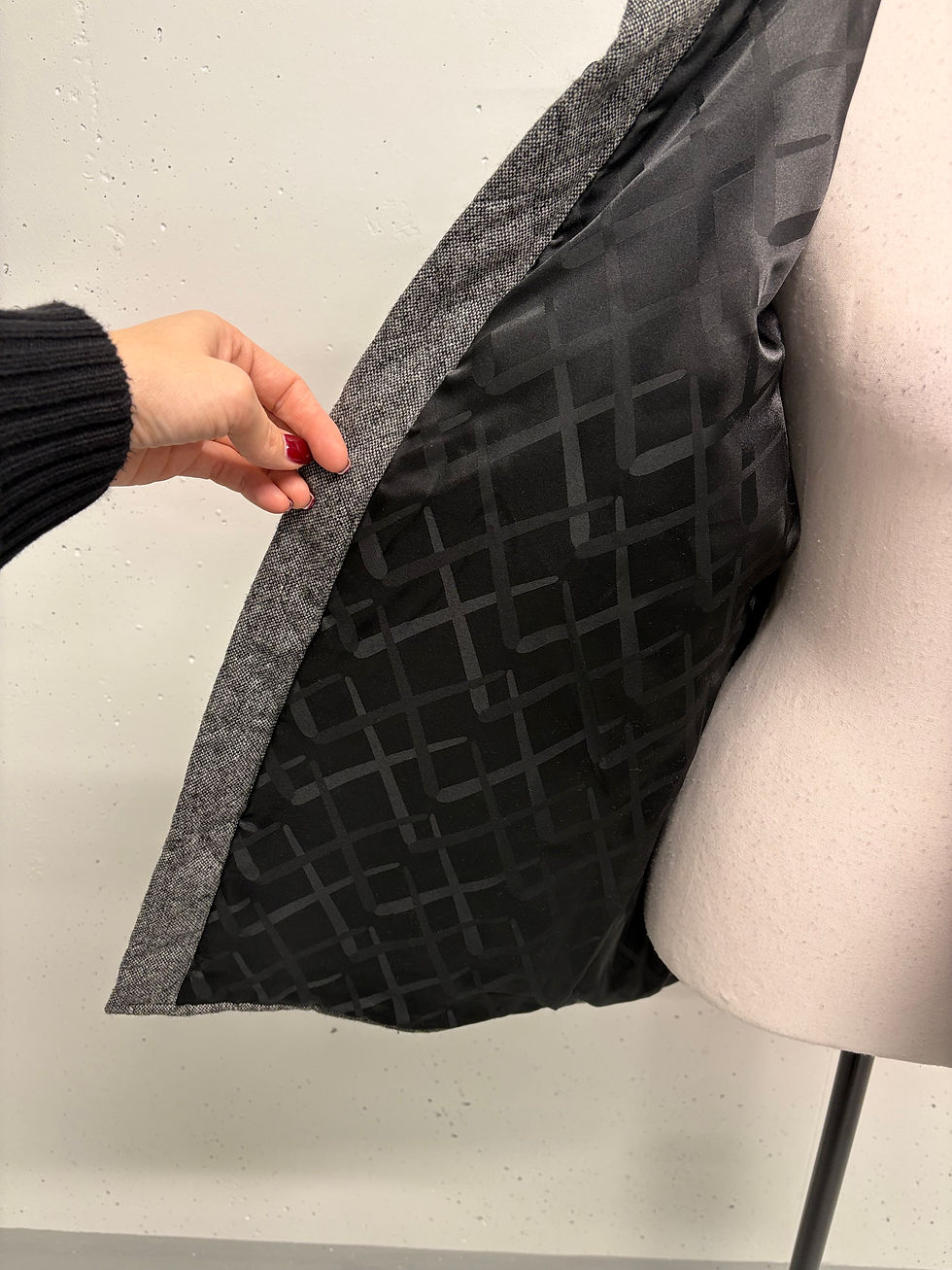 Miniaturbild: Graue Jacke mit Blick auf das schwarze Innenfutter. Hand hält Jacke