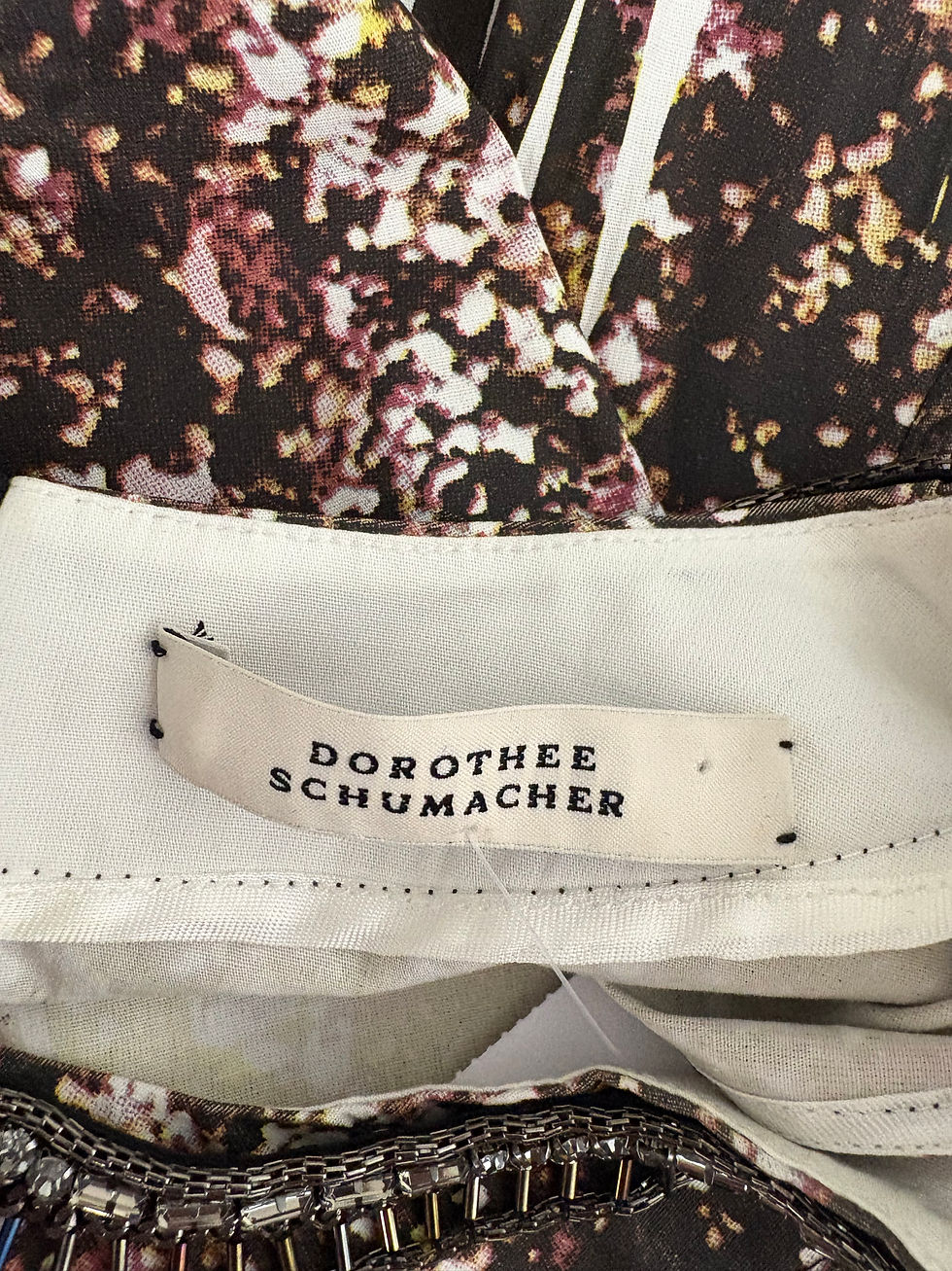 Miniaturbild: Nahaufnahme des DOROTHEE SCHUMACHER Etiketts an einem farbenfrohen Kleidungsstück. Details des Stoffes sichtbar.