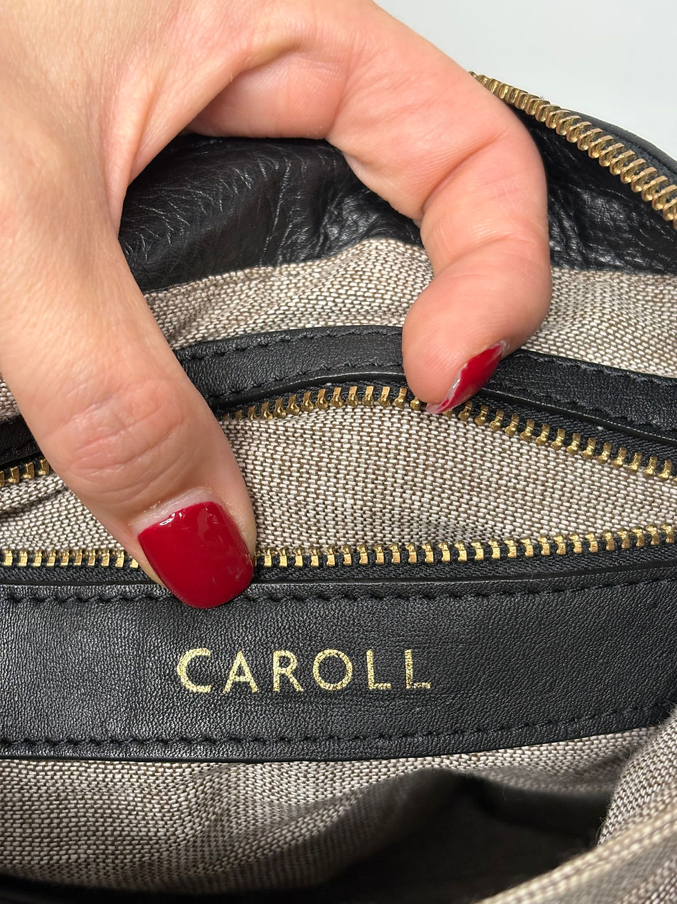 Miniaturbild: Nahaufnahme einer schwarzen CAROLL Handtasche mit goldenem Reißverschluss und Details.