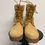 Miniaturbild: Paar gelbe Stiefel mit Schnürsenkeln auf einem schwarzen Tisch stehen.