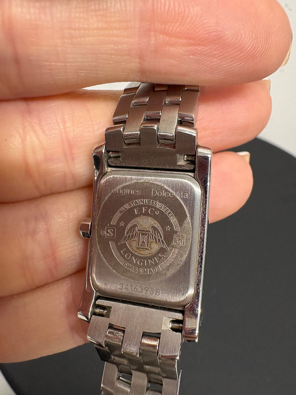Miniaturbild: Nahaufnahme einer silberfarbenen Longines-Uhr mit geprägten Details am Armgelenk.