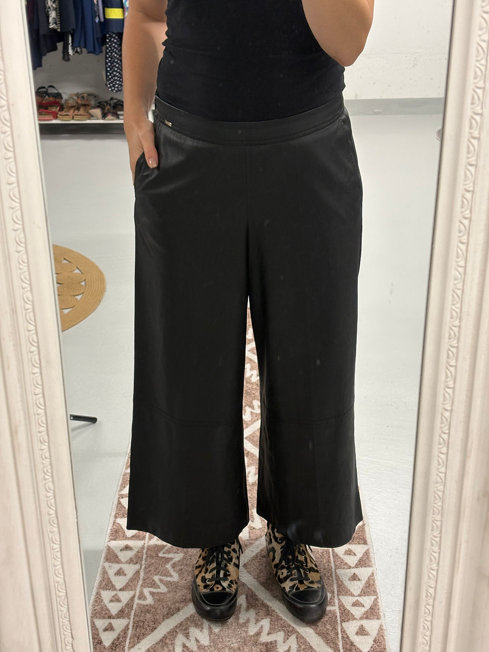 Eine Person trägt schwarze Hose im Spiegel mit einem weißen Rahmen.