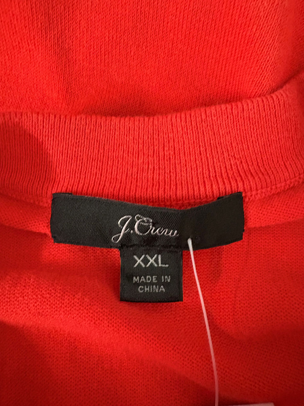 Miniaturbild: J.Crew label, XXL, Made in China, on a red garment, close-up shot.