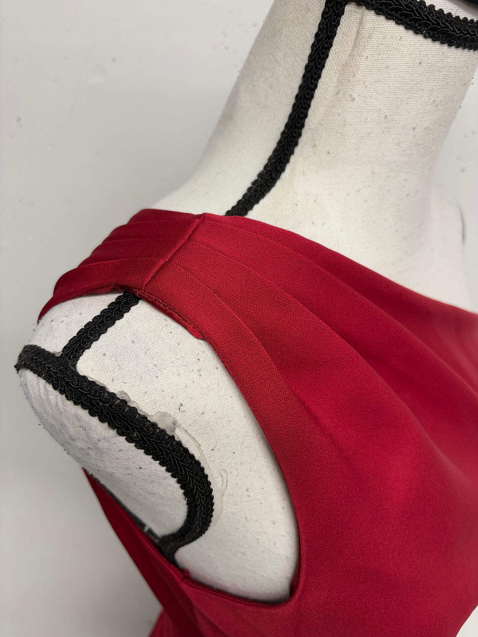 Miniaturbild: Drapiertes rotes Kleid Detail, elegant auf einer Schaufensterpuppe mit schwarzen Details.