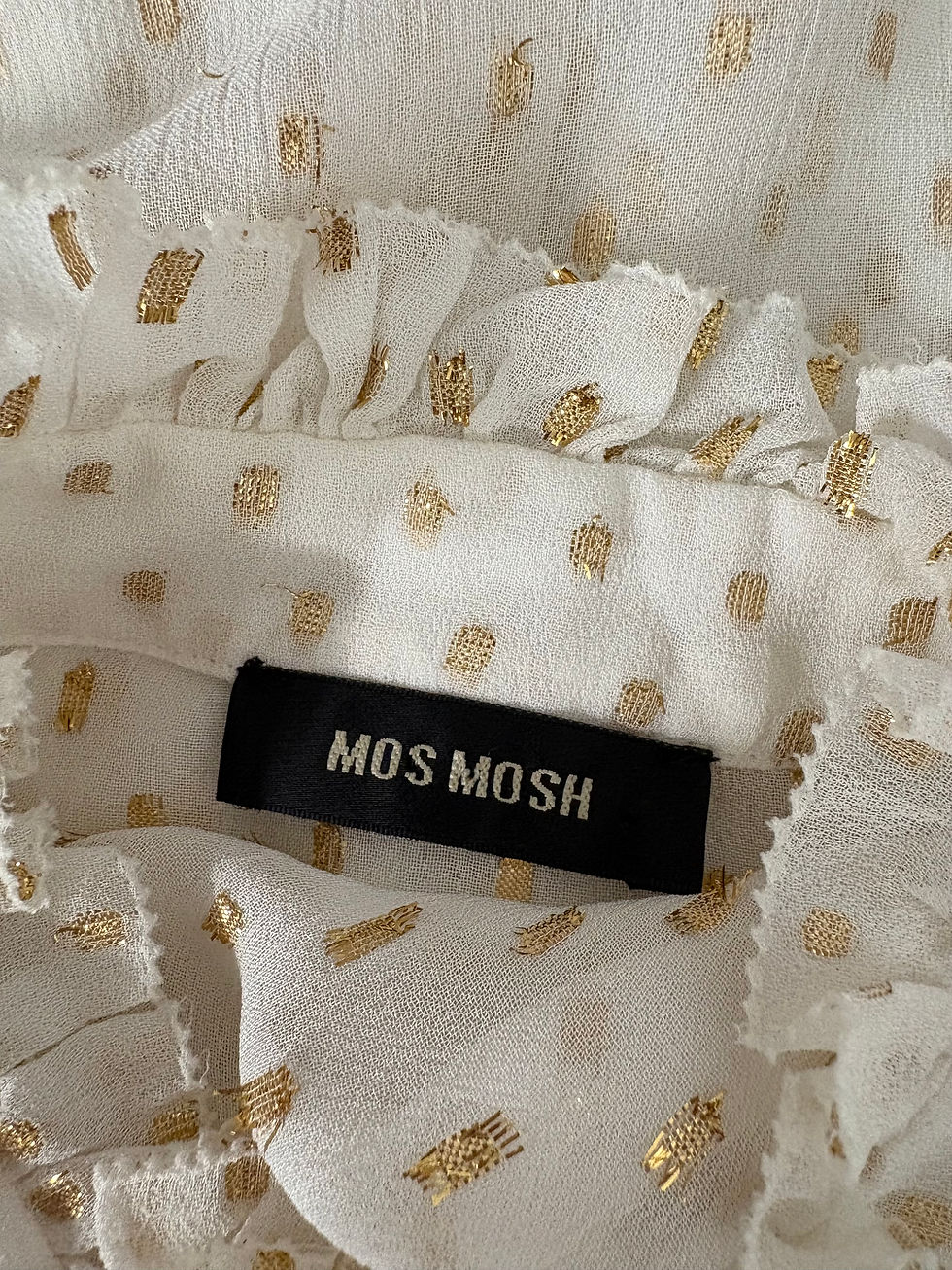 Miniaturbild: Nahaufnahme einer weißen Bluse mit Goldpunkten und MOS MOSH Label.