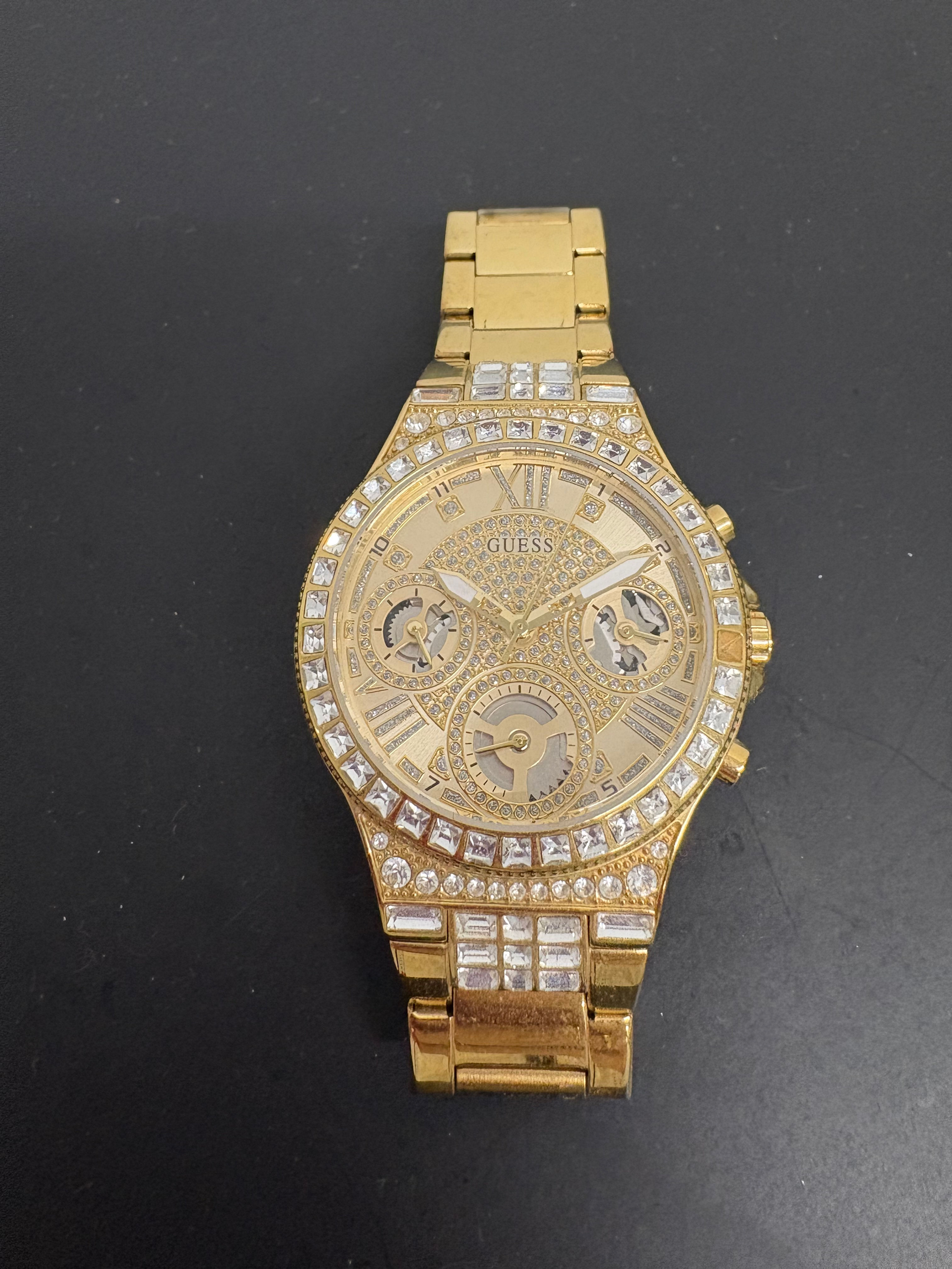 Goldene Guess-Uhr mit Strasssteinen und römischen Ziffern, nahaufnahme