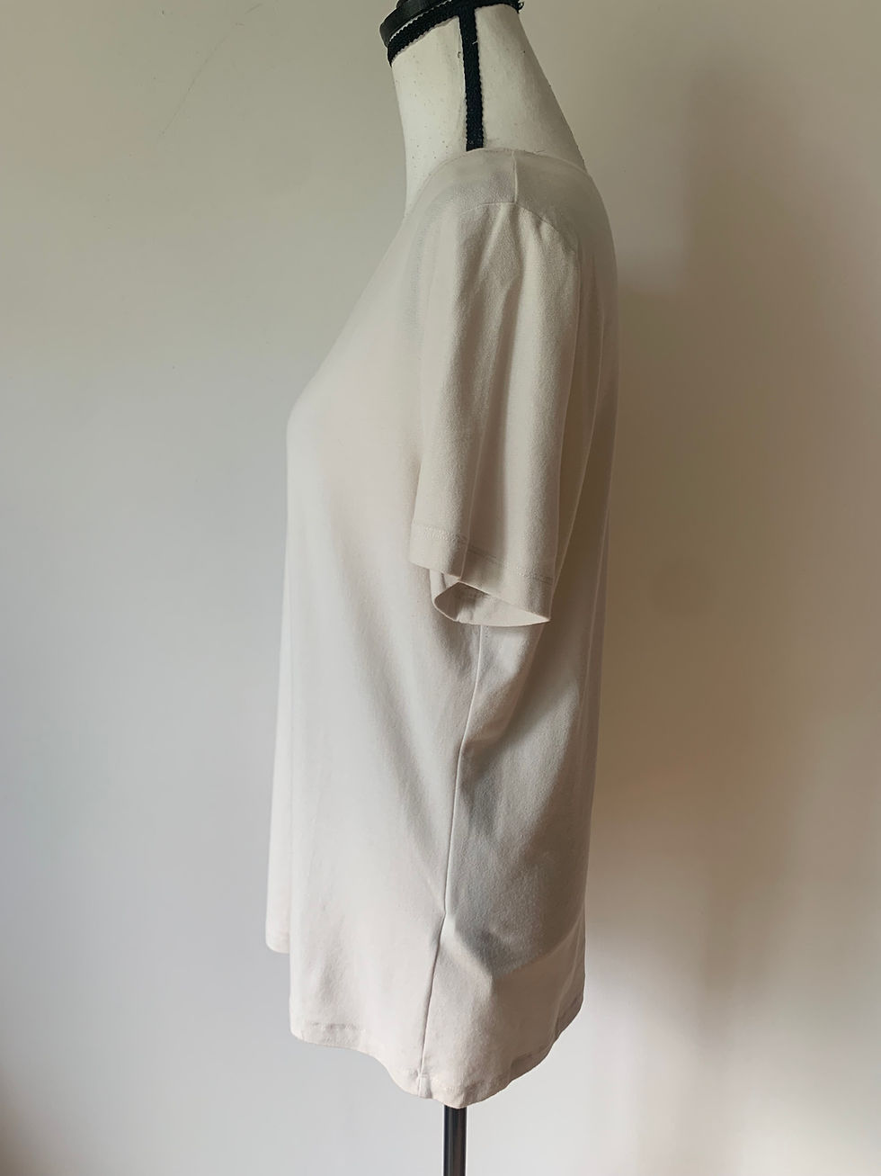 Miniaturbild: Beiges Damen-T-Shirt auf einer Büste, Detailaufnahme, Mode Sommerkleidung, seitlich vor weißem Hintergrund.