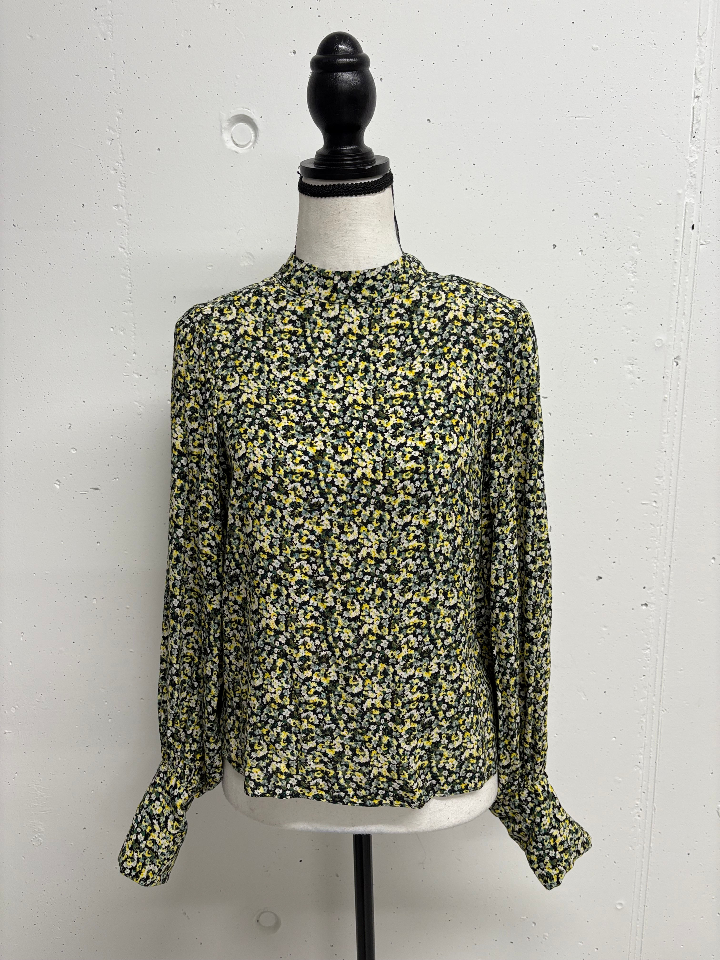Floral blouse on a mannequin against a white wall background.